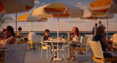 people sitting at tables with umbrellas over them on the deck of a cruise ship