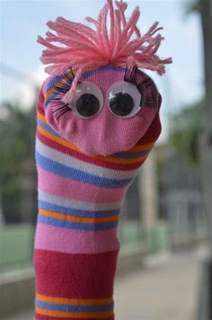 a pink sock with googly eyes and hair sticking out of it's side