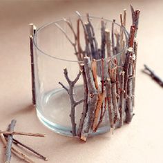 small branches are placed in a glass on the floor next to twig sticks that have fallen from them