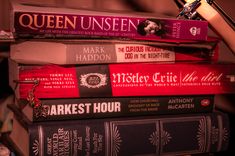 a stack of books sitting on top of each other next to a lamp and desk