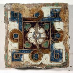 an old tile with blue and brown designs on it