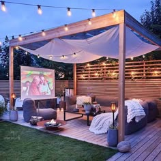 an outdoor entertainment area is lit up with string lights and white curtains on the roof