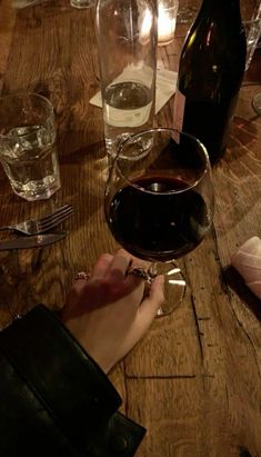 a person holding a wine glass on top of a wooden table