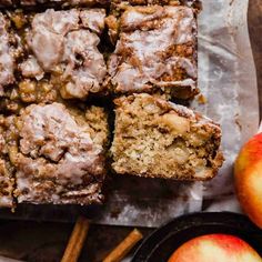 apple cinnamon coffee cake sliced on top of parchment paper next to apples and cinnamon sticks