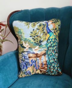 a peacock pillow sitting on top of a blue chair