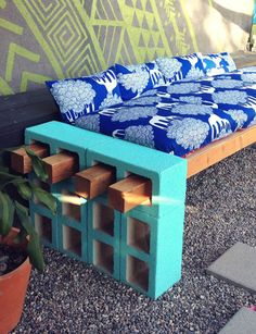 a bed made out of wooden blocks sitting on top of gravel next to a potted plant