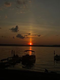 the sun is setting over water with boats in it and people standing on the dock