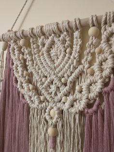 a crocheted wall hanging with beads and tassels on it's sides