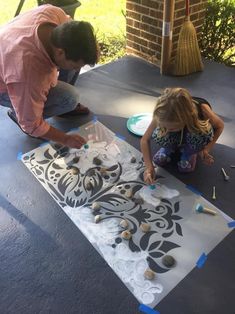 two people sitting on the ground working on an art project