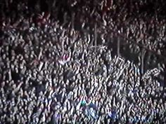 a large group of people standing around each other in the middle of a crowd at night