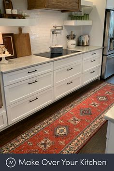 a kitchen with white cabinets and an area rug