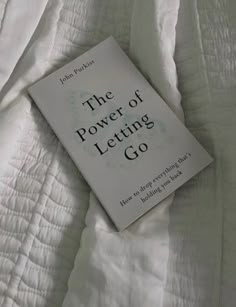 the power of letting go book laying on top of a white comforter covered bed