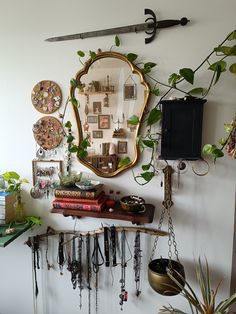 there is a mirror on the wall with many things hanging from it and some plants