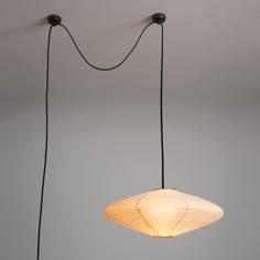 two lamps hanging from the ceiling in a room with gray walls and flooring, one light is turned on