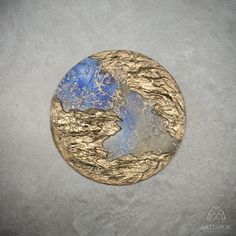 a gold and blue plate sitting on top of a white table next to a gray wall