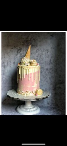 a pink and gold cake with an ice cream cone sticking out of it's top