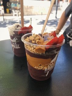 two cups with ice cream and strawberries in them sitting on a table next to each other