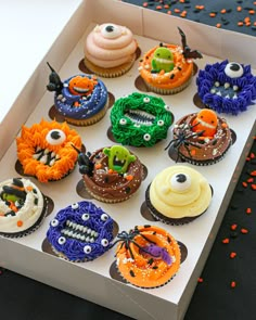 a box filled with cupcakes covered in frosting and decorated like monster faces