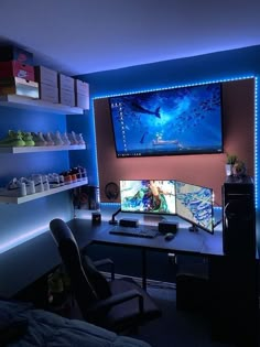 a computer desk with two monitors on it in front of a blue wall and shelves