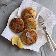 three muffins on a white plate with lemon wedges and a fork next to it