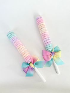 two pastel colored candy sticks with bows on them