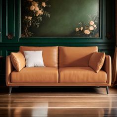 an orange leather couch in front of a green wall with flowers on it and two white pillows