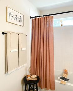 a bathroom with a tub, shower curtain and stool