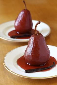 two white plates topped with pears covered in red sauce and melted chocolate on them