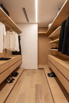 a walk in closet with wooden shelves and shoes on the floor, along with white shirts