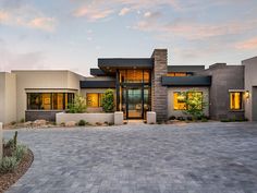 a modern house with large driveway and landscaping