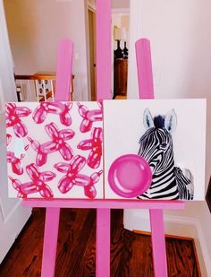 a pink easel with zebras on it and pictures in the back ground next to a doorway