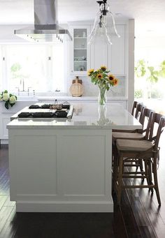 a kitchen with white cabinets and sunflowers on the island