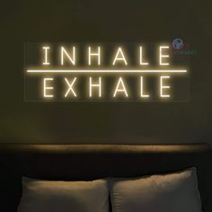 an inhale exhale neon sign is lit up on the wall above a bed