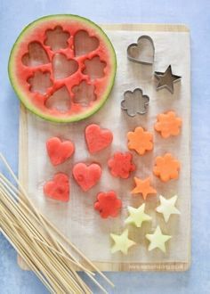 a watermelon slice, cookie cutters and star shaped cookies on a cutting board