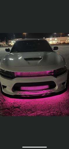 the front end of a white car with pink lights