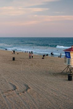 the beach is crowded with people and umbrellas on a cloudy day at sunset or sunrise