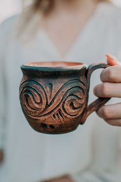 a woman holding a brown cup in her hands