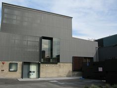 an empty parking lot in front of a building with large windows on the side of it