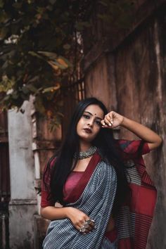 a woman with long black hair wearing a red and white sari posing for the camera