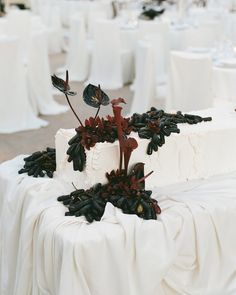 there is a wedding cake with flowers on the top and black leaves on the bottom