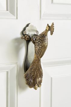 a decorative door handle with a bird design on it's side, hanging from a white wall