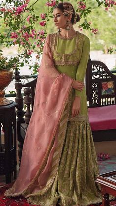 a woman wearing a green and pink lehenga