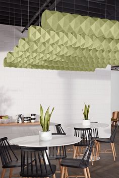 a room with tables, chairs and plants hanging from the ceiling above them is a white tiled wall