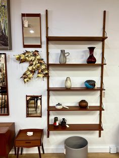 a shelf with vases and other items on it in a room that has white walls