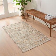 a wooden bench sitting on top of a hard wood floor next to a rug and potted plant