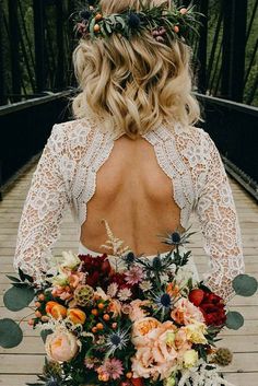 a woman with flowers in her hair is standing on a bridge wearing a white dress