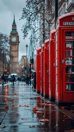 a row of red telephone booths sitting on the side of a street next to a tall clock tower