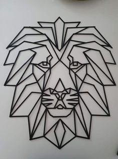 a paper cut lion head on a white wall with a clock in the back ground