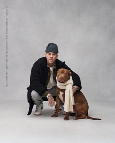 a man kneeling down next to a dog with a scarf around it's neck