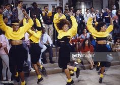 dancers in yellow and black outfits are dancing on the steps while people watch from behind them